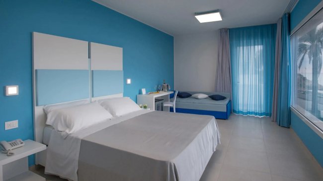 Camera da letto con pareti blu, letto matrimoniale e un'altra alcova.