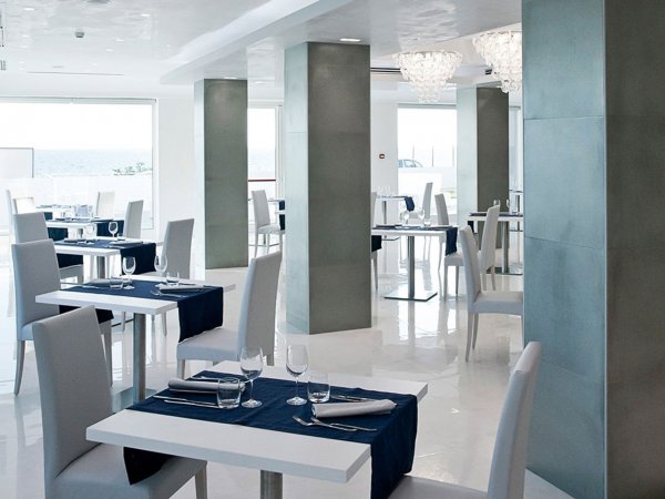 Ristorante elegante con tavoli bianchi, sedie grigie e tovagliette blu.