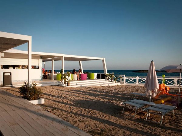 Terrazza sulla spiaggia con sedie colorate, sedie a sdraio e vista mare.