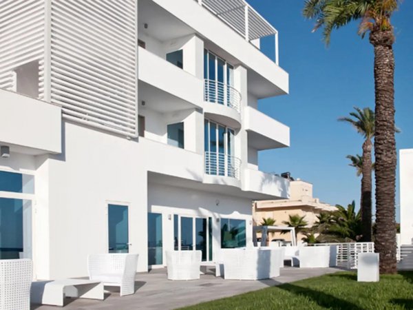 Edificio moderno bianco con balconi e sedie; vista di giorno soleggiato.