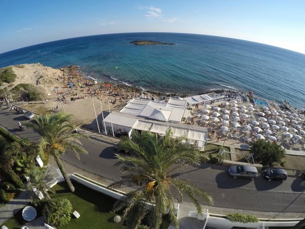 Vista dall'alto di una spiaggia affollata con ombrelloni e mare.