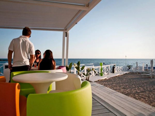 Due persone sedute a un tavolo colorato vicino alla spiaggia, con vista sul mare.