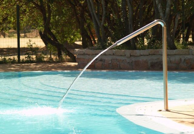 Una piscina con un getto d'acqua curvo che si tuffa nell'acqua blu.