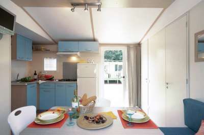 Cucina moderna con mobili azzurri, tavolo apparecchiato e frigorifero bianco.