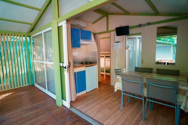 Veranda con cucina blu, tavolo e sedie.