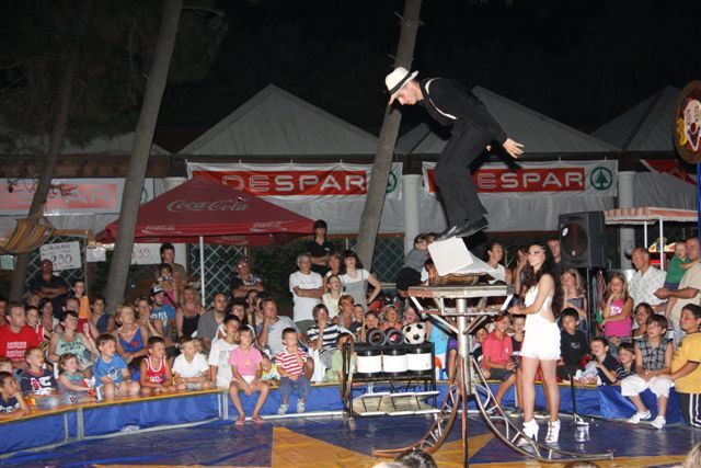 Un acrobata in equilibrio su una piattaforma di fronte a una folla di spettatori.