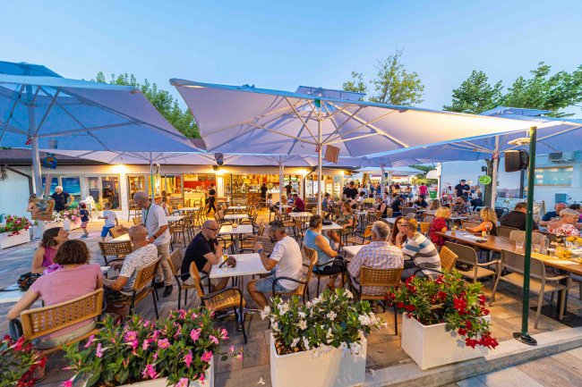 Ristorante all'aperto con persone sedute.