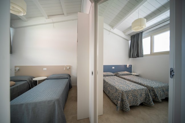 Camera con letti singoli separati da una parete.