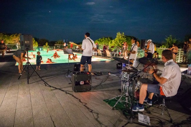Concerto serale accanto a una piscina illuminata.