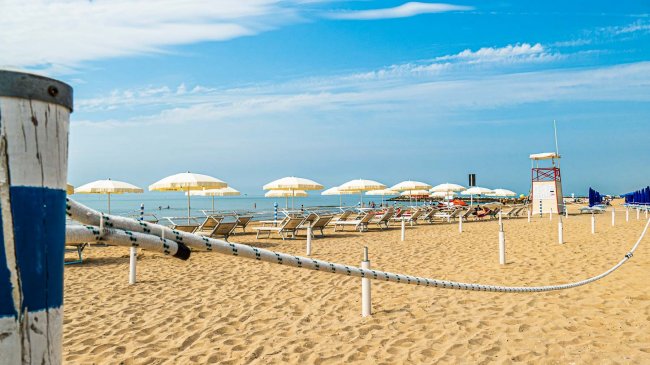 Spiaggia con ombrelloni gialli e mare.