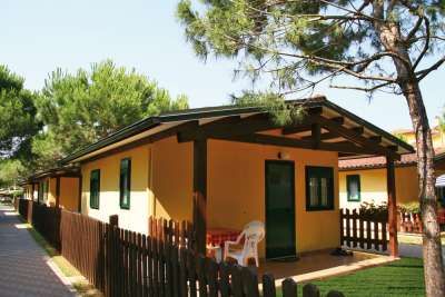 Casa gialla con veranda e piccola recinzione in legno.